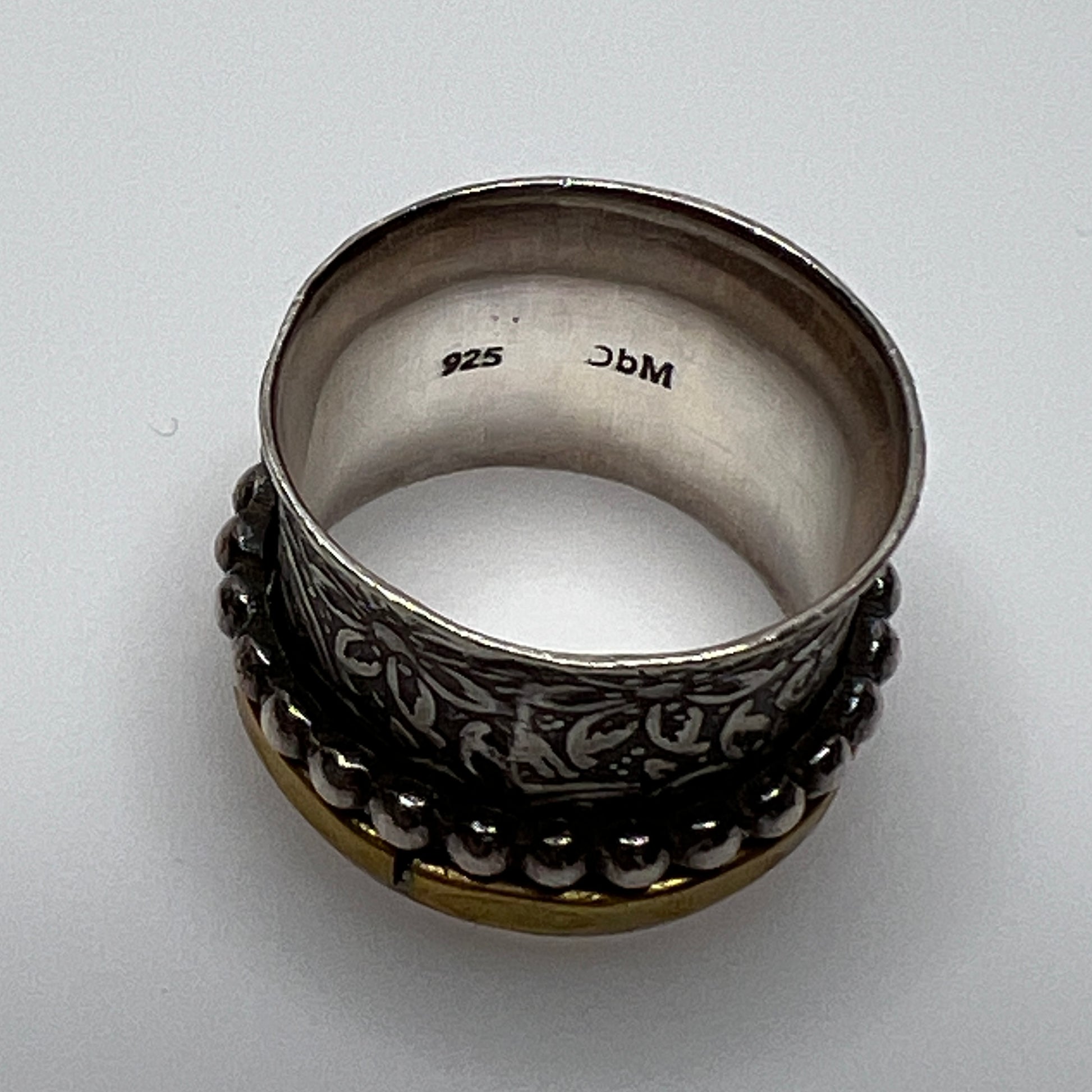 Wide sterling silver spinner ring with floral embossing, brass band, and beaded spinner