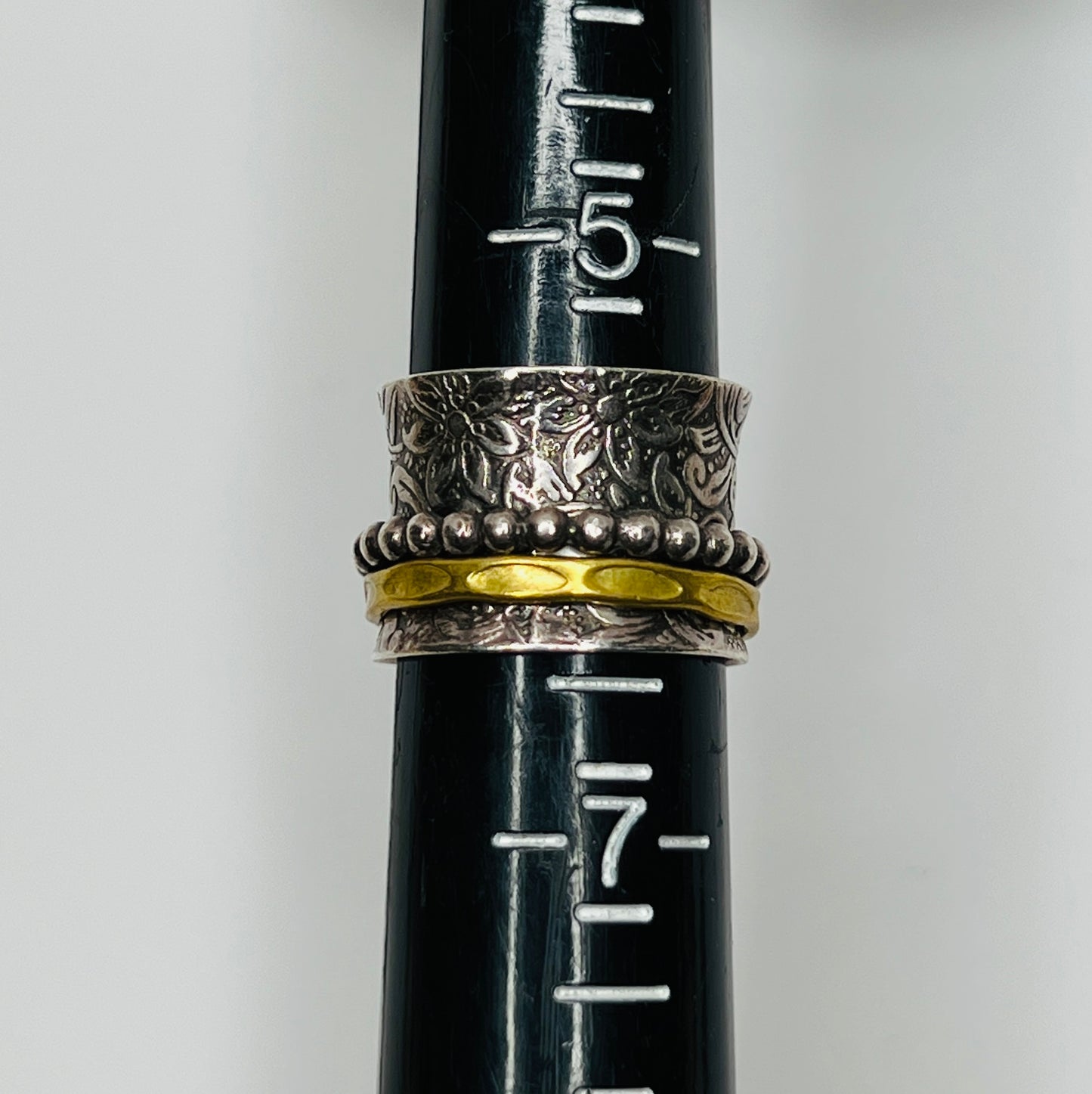 Wide sterling silver spinner ring with floral embossing, brass band, and beaded spinner