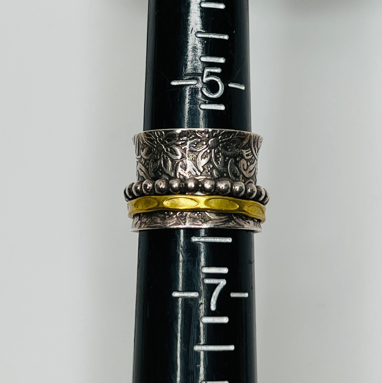 Wide sterling silver spinner ring with floral embossing, brass band, and beaded spinner