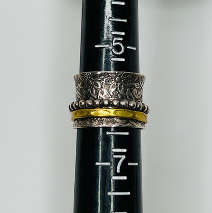 Wide sterling silver spinner ring with floral embossing, brass band, and beaded spinner