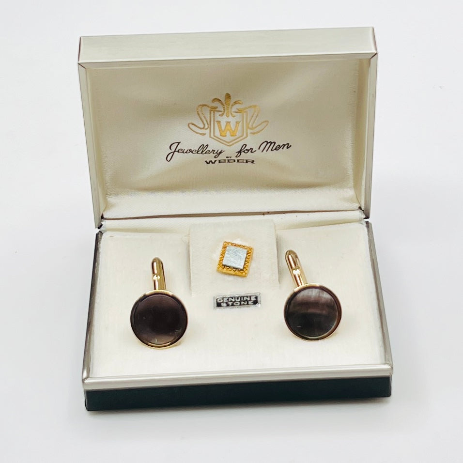 Jewelry set with cufflinks and a tie clip in an open jewelry box on a white background
