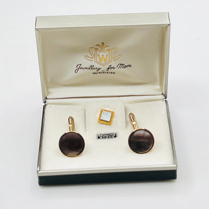 Jewelry set with cufflinks and a tie clip in an open jewelry box on a white background