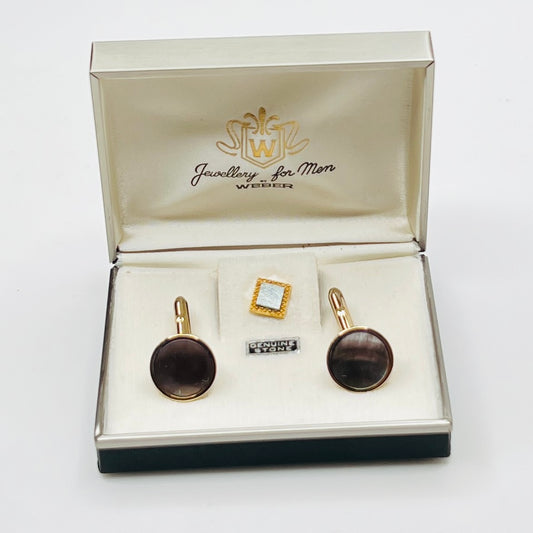 Jewelry set with cufflinks and a tie clip in an open jewelry box on a white background