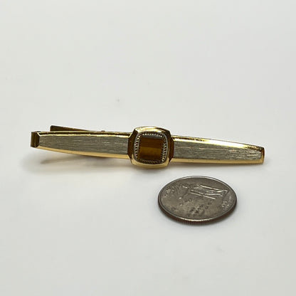 Close-up of goldtone tie bar with square tiger’s eye stone
