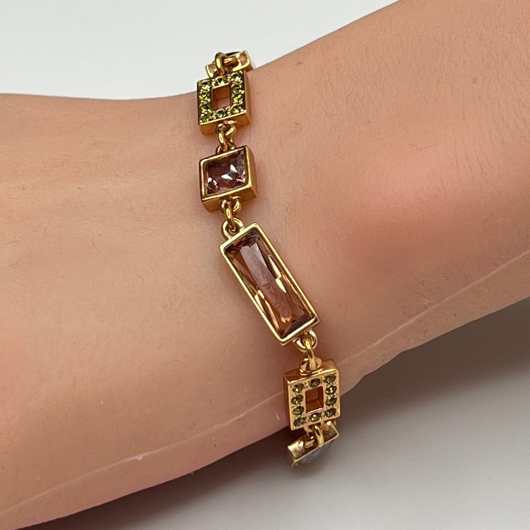 Gold-tone bracelet on wrist with topaz and mauve Swarovski crystals