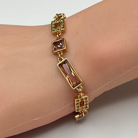 Gold-tone bracelet on wrist with topaz and mauve Swarovski crystals