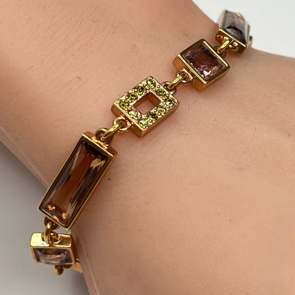 Gold-tone bracelet on wrist with topaz and mauve Swarovski crystals