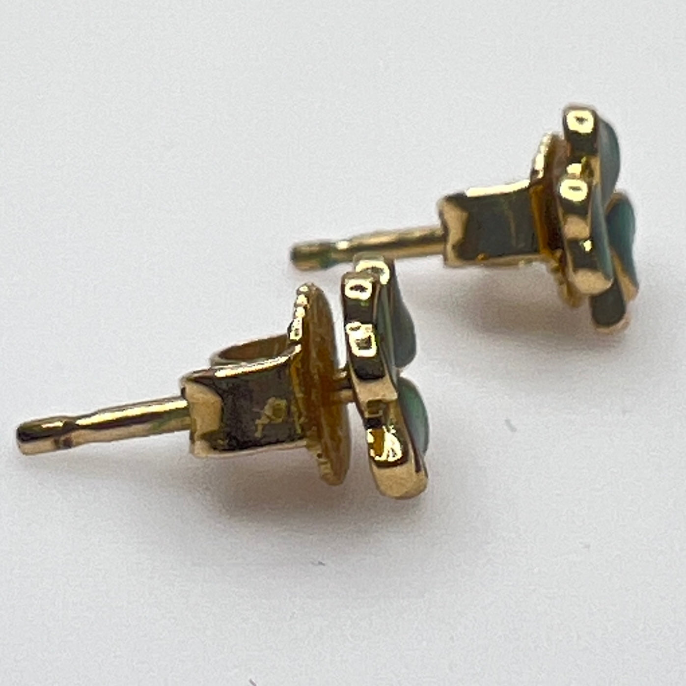 Tiny 14K gold shamrock stud earrings with green enamel cloverleaf design