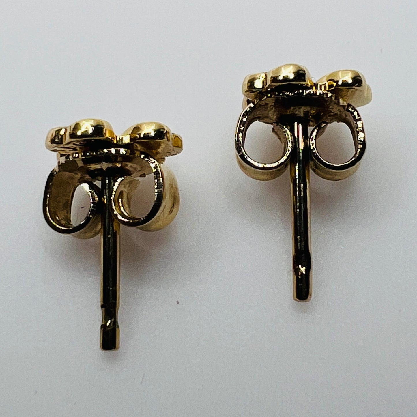 Tiny 14K gold shamrock stud earrings with green enamel cloverleaf design