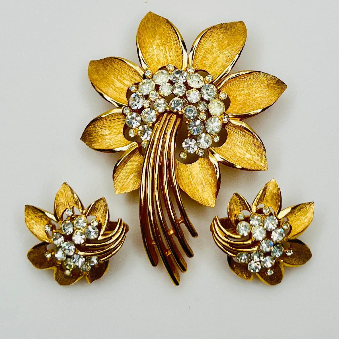 Trifari gold-tone floral brooch with matching clip-on earrings and rhinestone centers