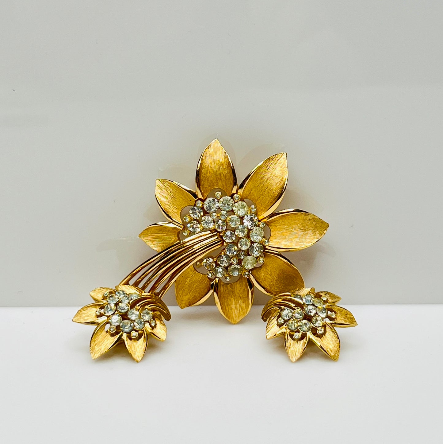 Trifari gold-tone floral brooch with matching clip-on earrings and rhinestone centers