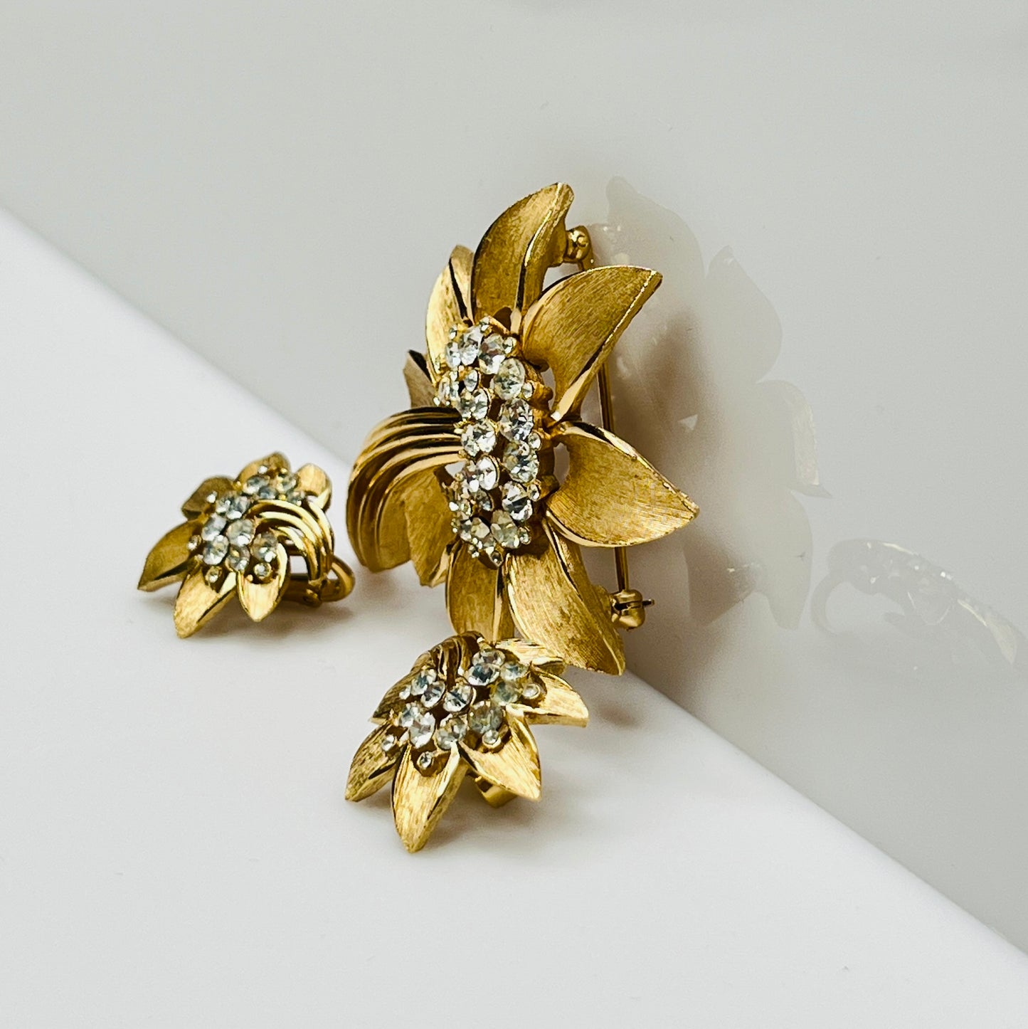 Trifari gold-tone floral brooch with matching clip-on earrings and rhinestone centers