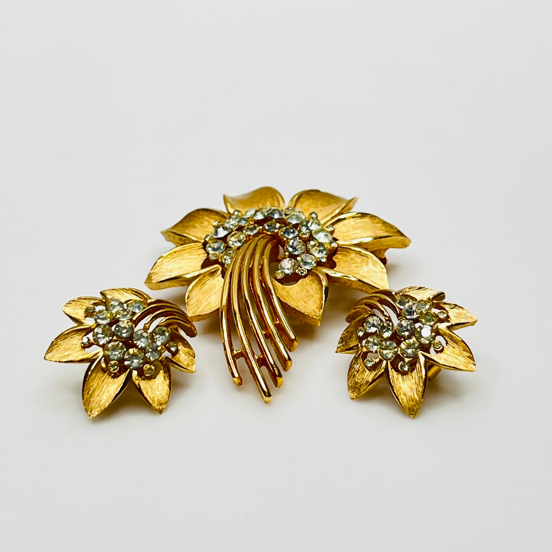 Trifari gold-tone floral brooch with matching clip-on earrings and rhinestone centers