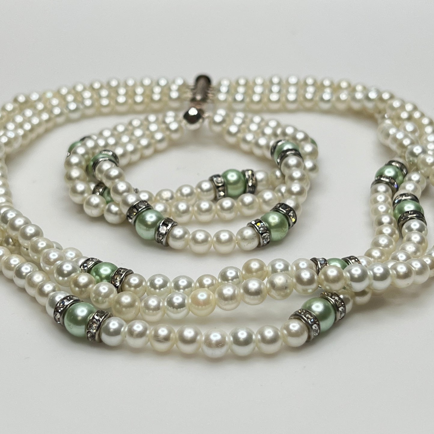 Three-strand faux pearl necklace and bracelet set with sage green pearls and rhinestone spacers.
