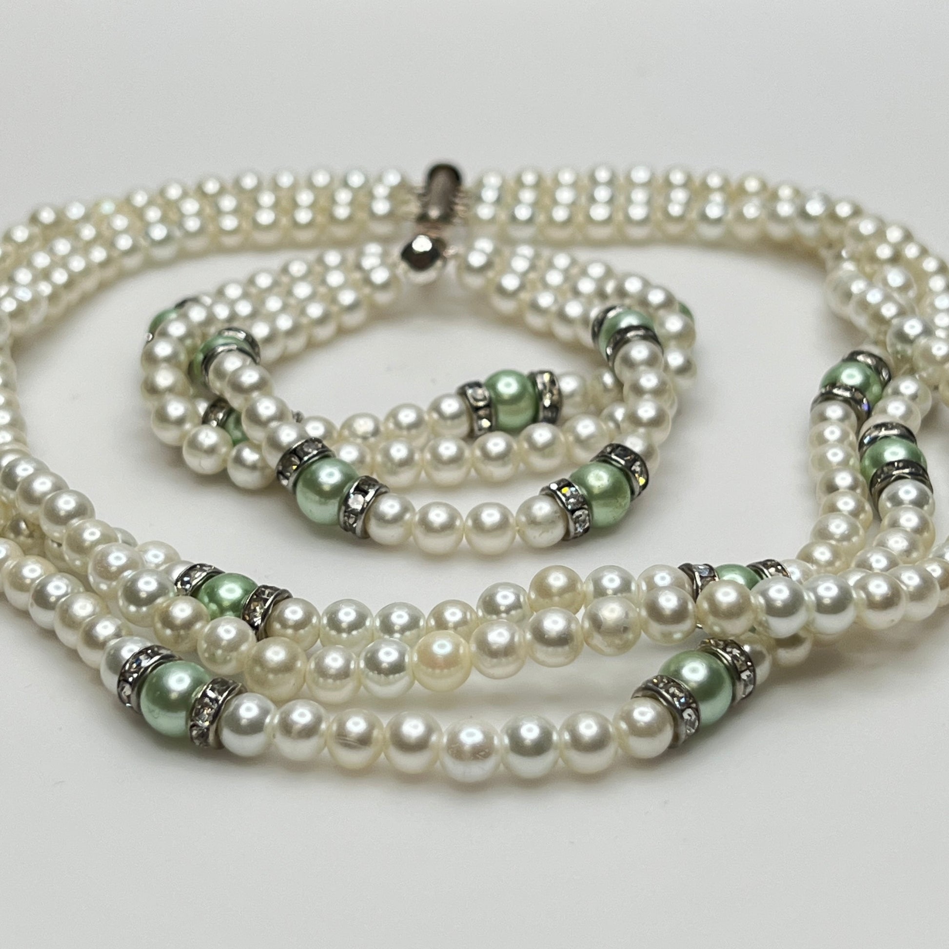 Three-strand faux pearl necklace and bracelet set with sage green pearls and rhinestone spacers.