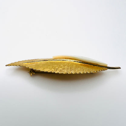 Side view of vintage 1950s gold-tone botanical brooch showing raised mother of pearl leaf and dimensional metal construction.