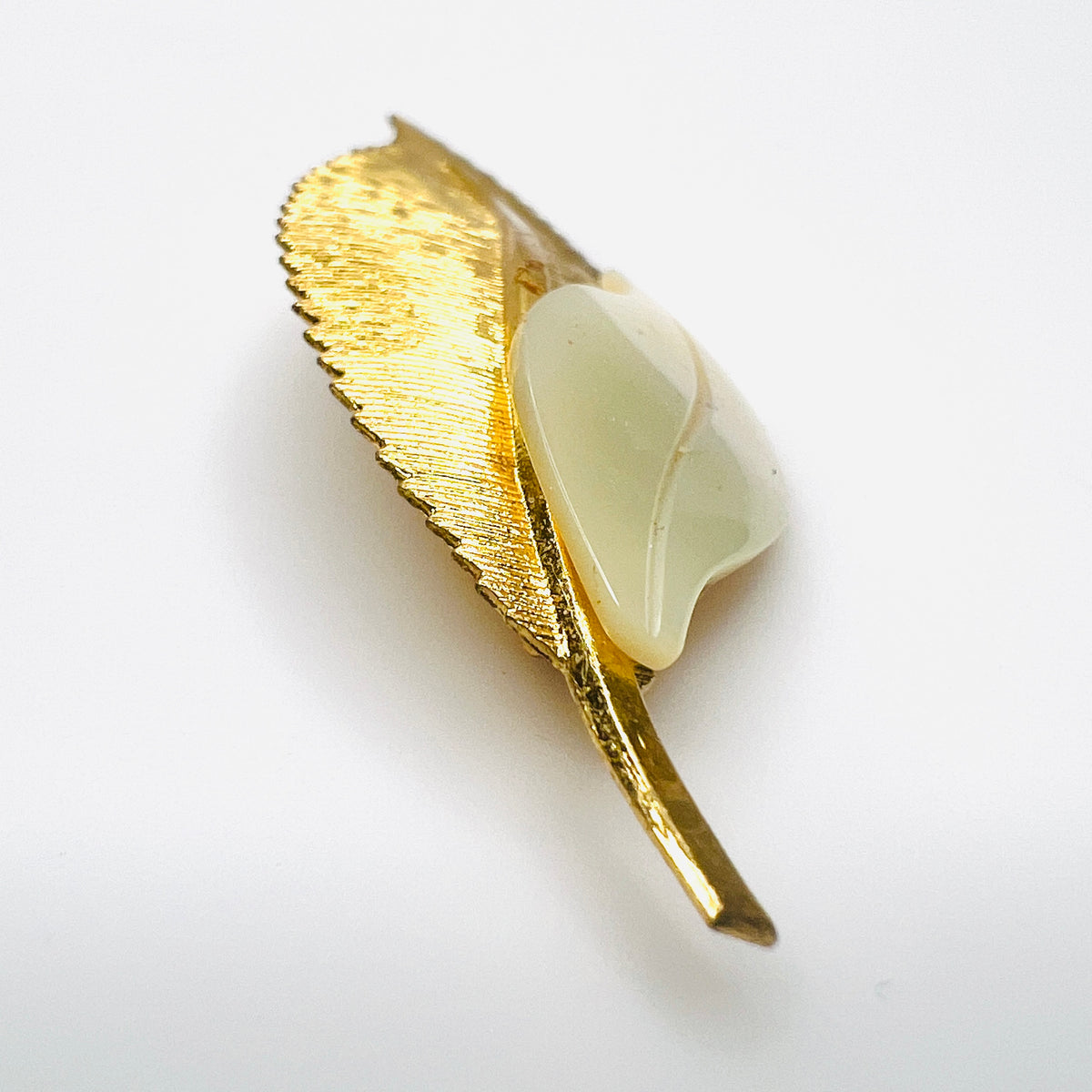Side view of vintage 1950s gold-tone botanical brooch showing raised mother of pearl leaf and dimensional metal construction.