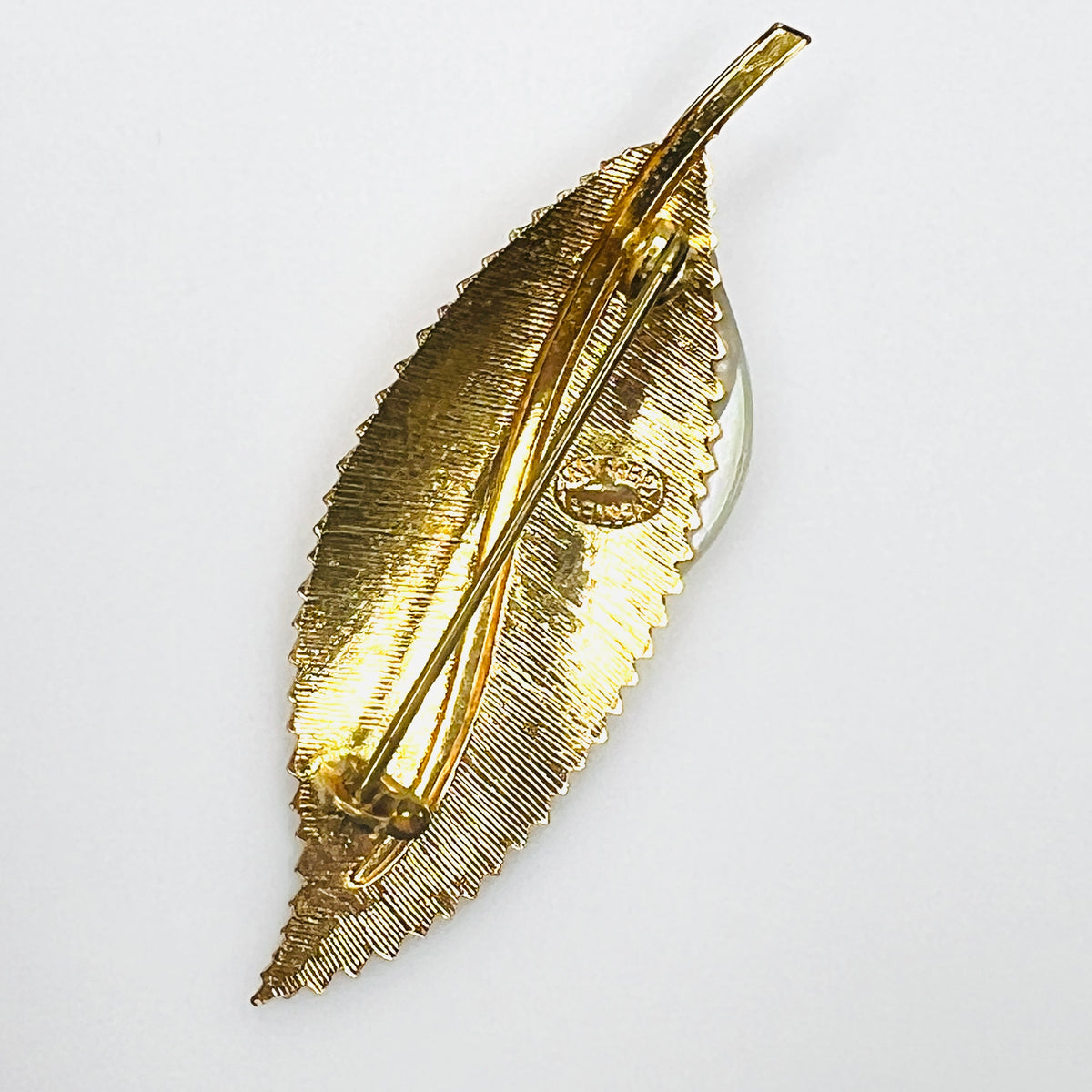 Reverse of vintage West Germany gold-tone leaf brooch showing rollover safety clasp and textured metal backing.