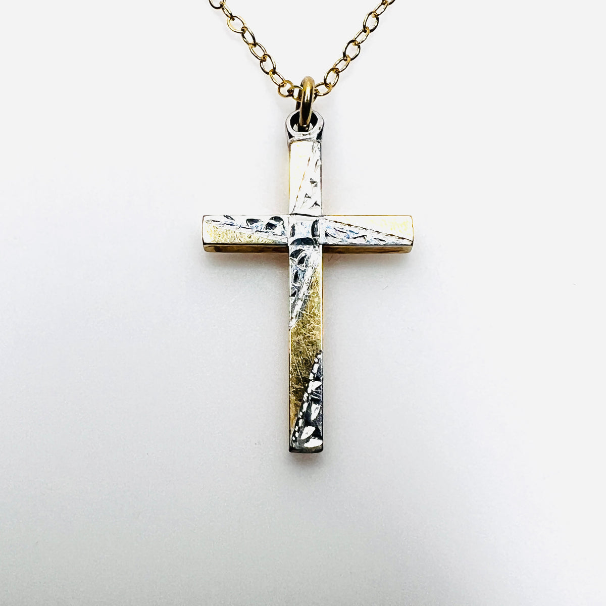 Close-up of Carl-Art two-tone cross pendant with etched silver-tone accents