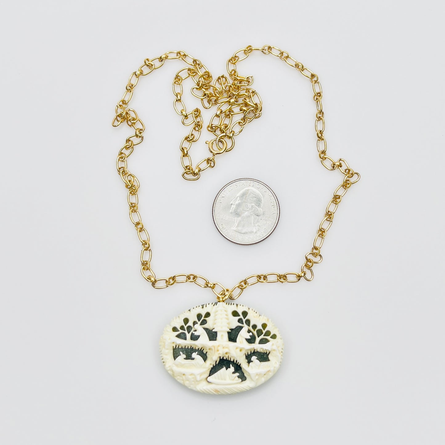 Detailed carved pendant with figures and trees on jade backing