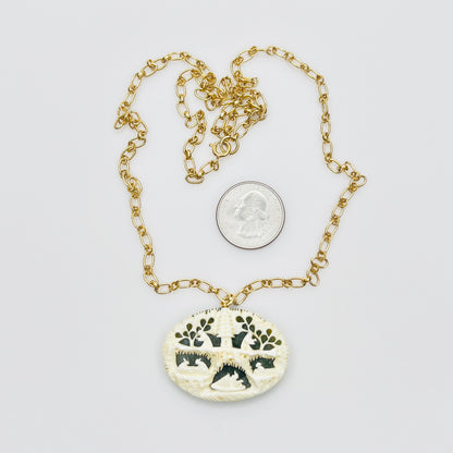 Detailed carved pendant with figures and trees on jade backing