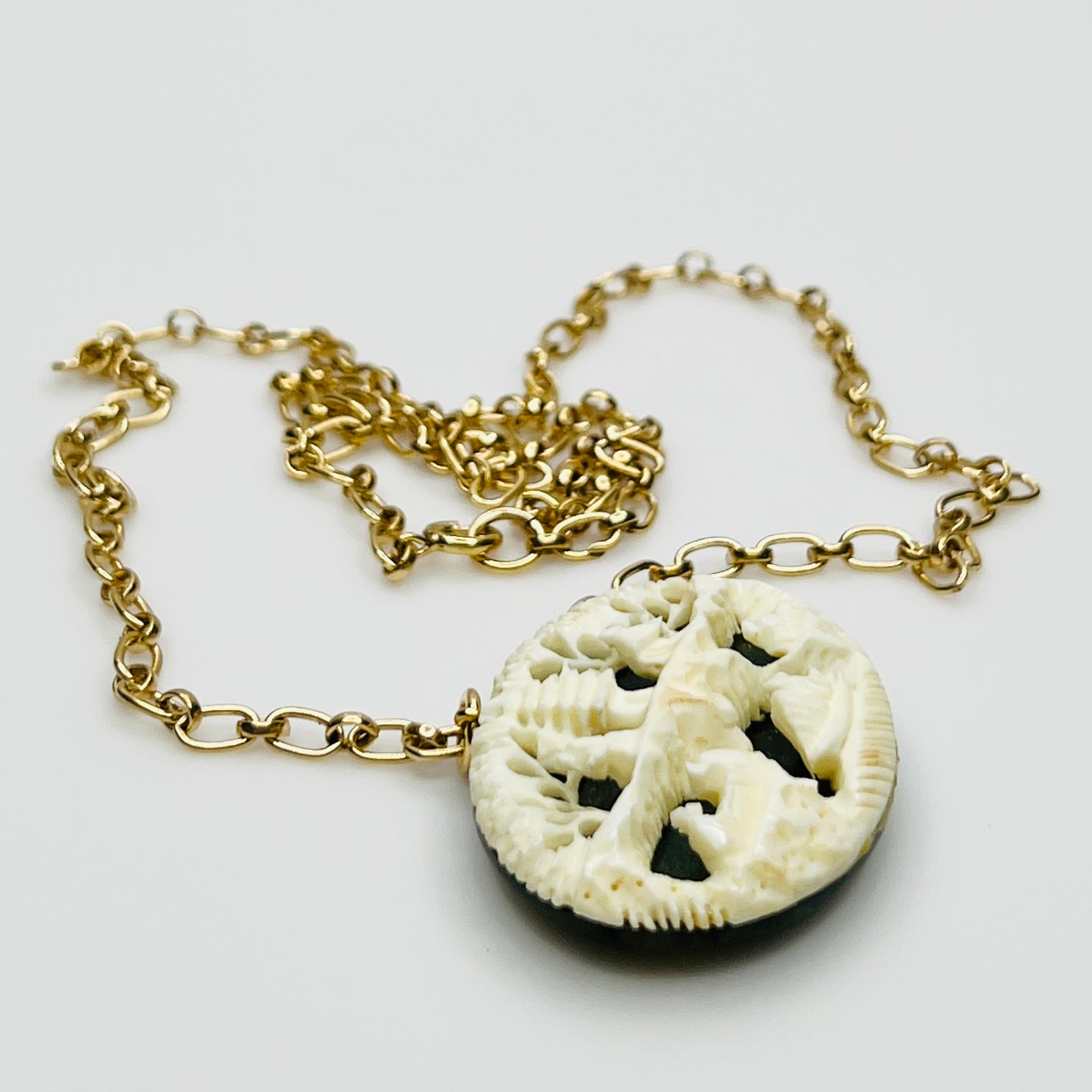 Detailed carved pendant with figures and trees on jade backing