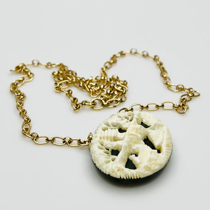 Detailed carved pendant with figures and trees on jade backing