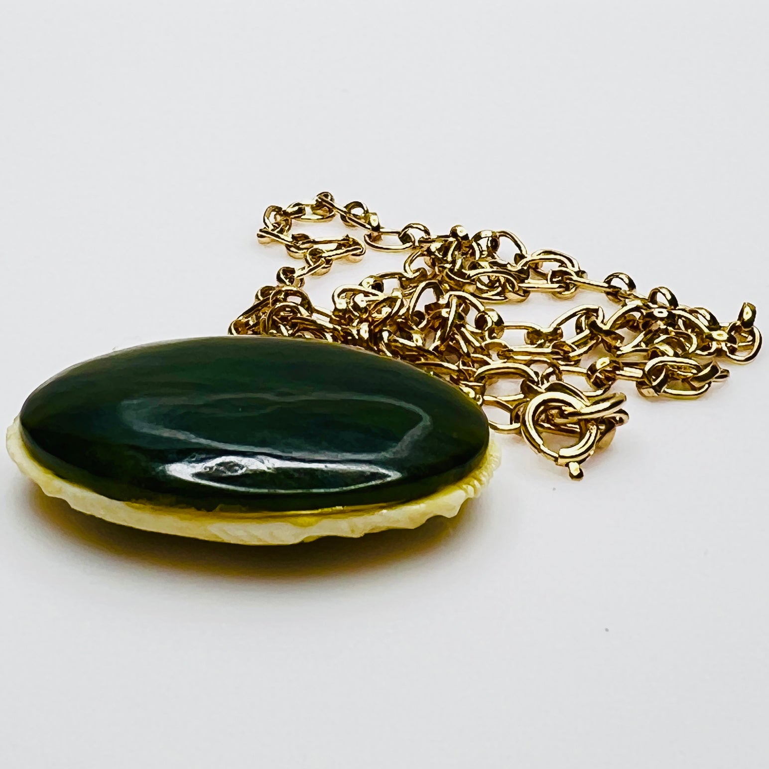 Back view showing polished green jade disc and gold chain