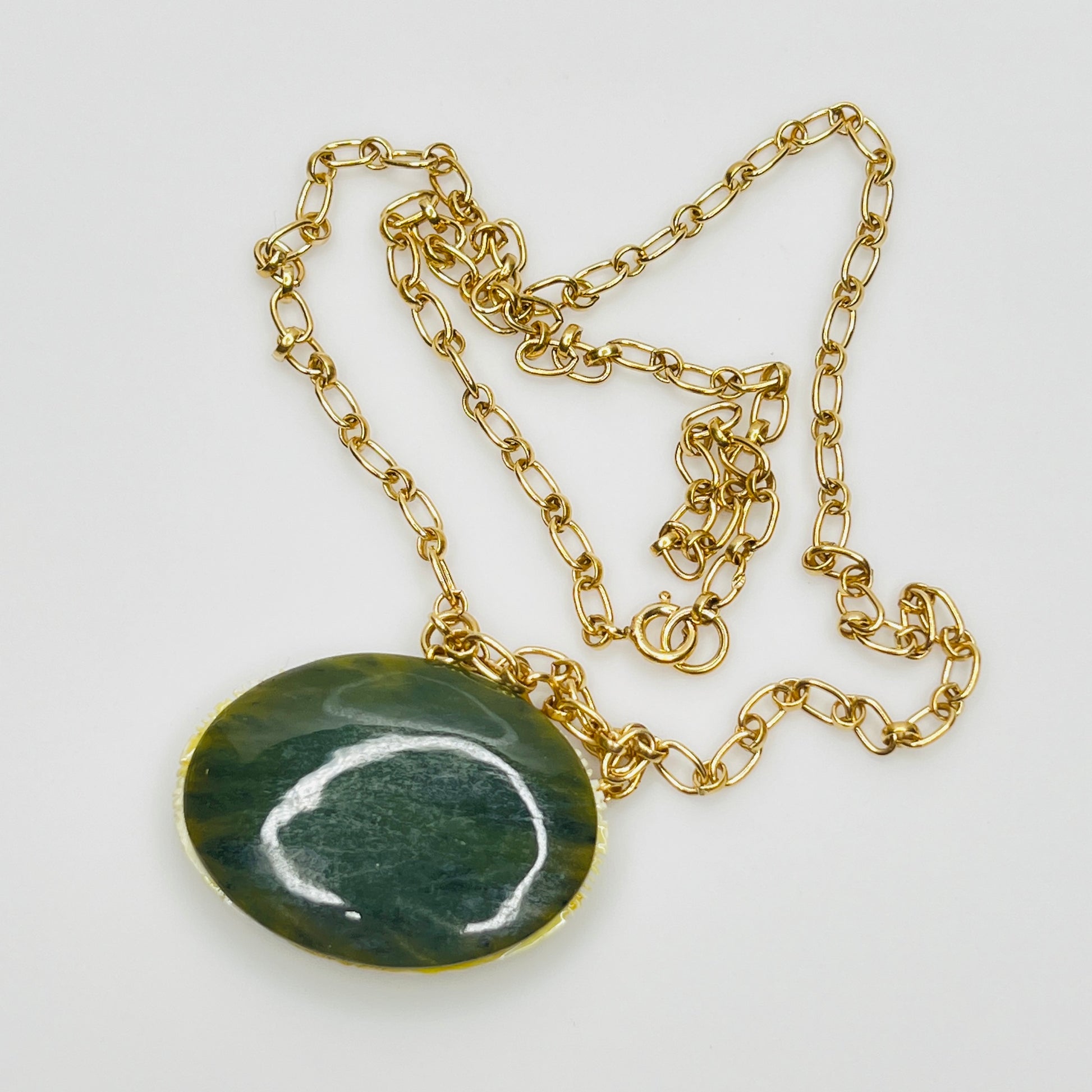 Back view showing polished green jade disc and gold chain