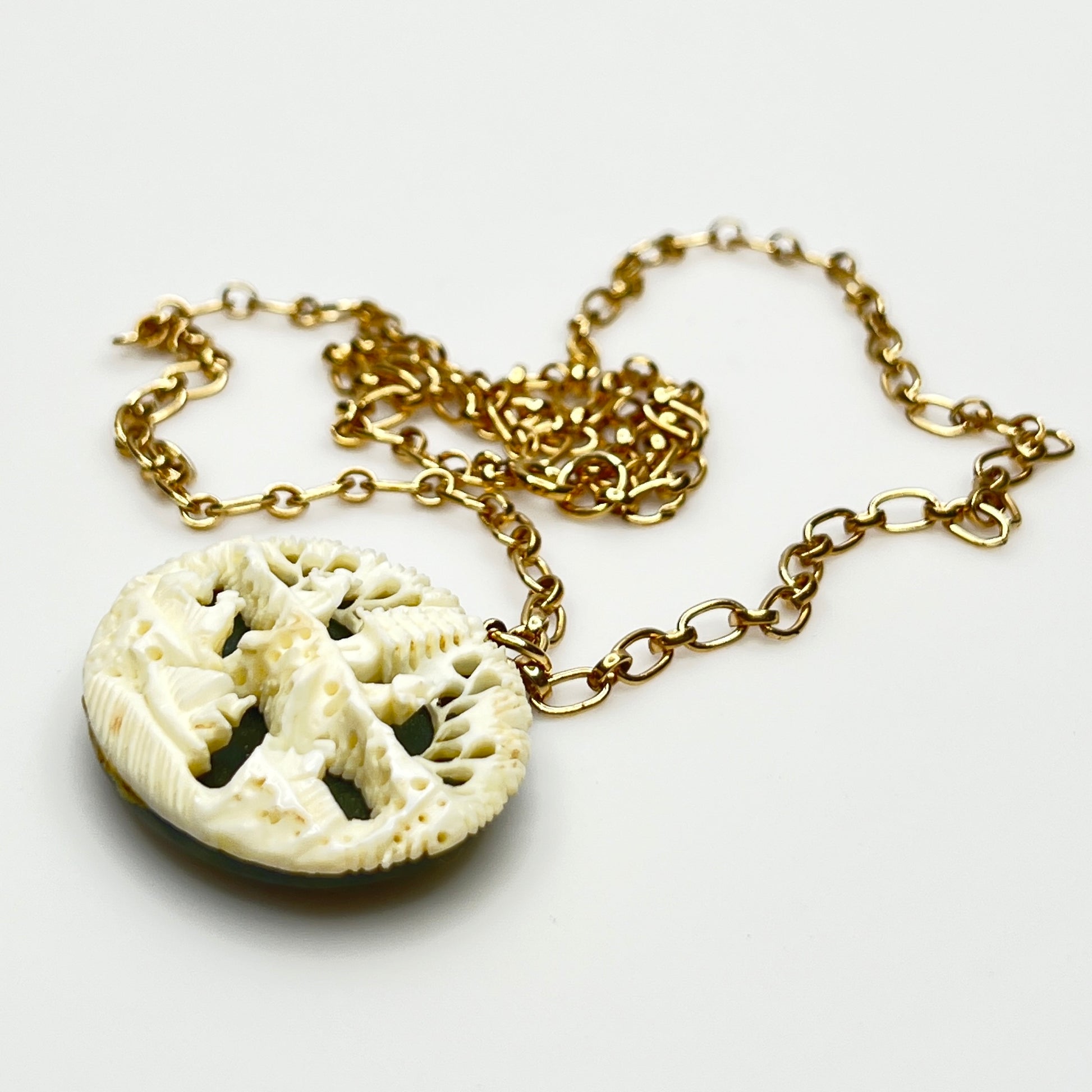 Detailed carved pendant with figures and trees on jade backing