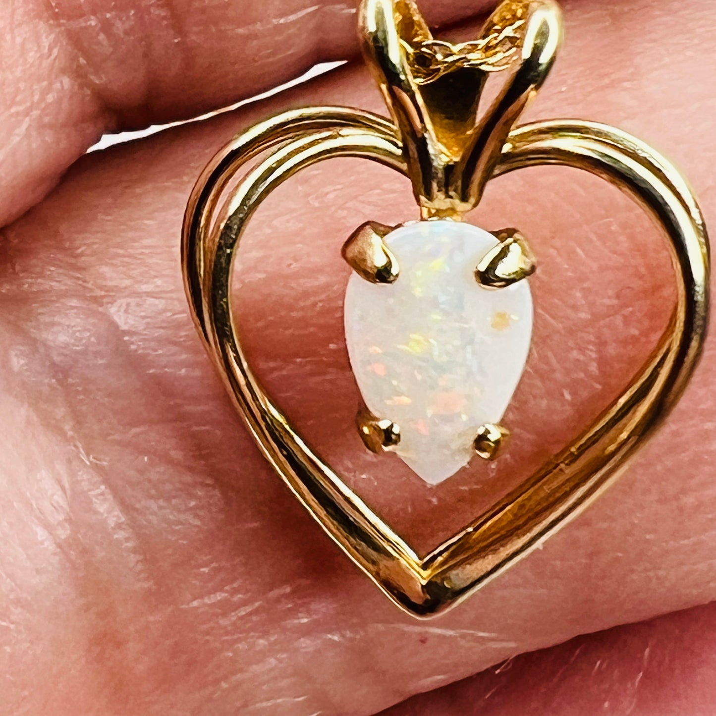 Close up genuine opal stone prong set in gold heart pendant