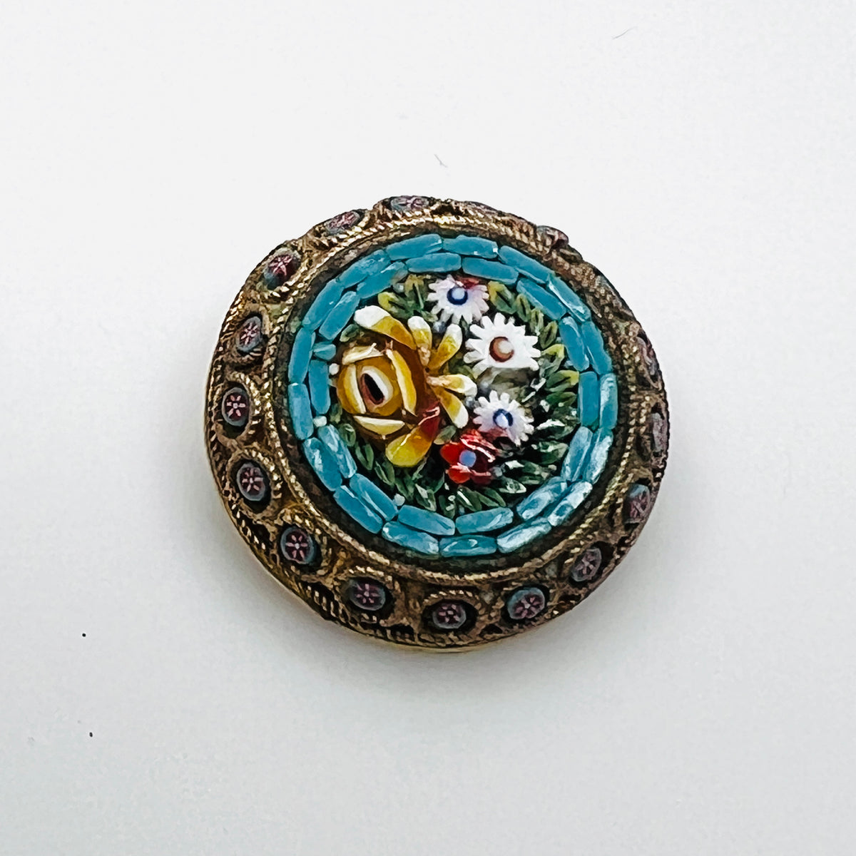 Italian micro mosaic floral brooch with a turquoise-blue border, ornate gold-tone frame, and loss to one white flower.