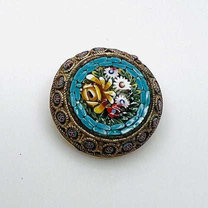 Italian micro mosaic floral brooch with a turquoise-blue border, ornate gold-tone frame, and loss to one white flower.