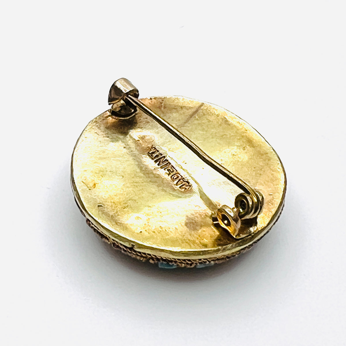 Reverse of round Italian mosaic brooch showing aged gold-tone metal, Made in Italy stamp, and C-clasp.