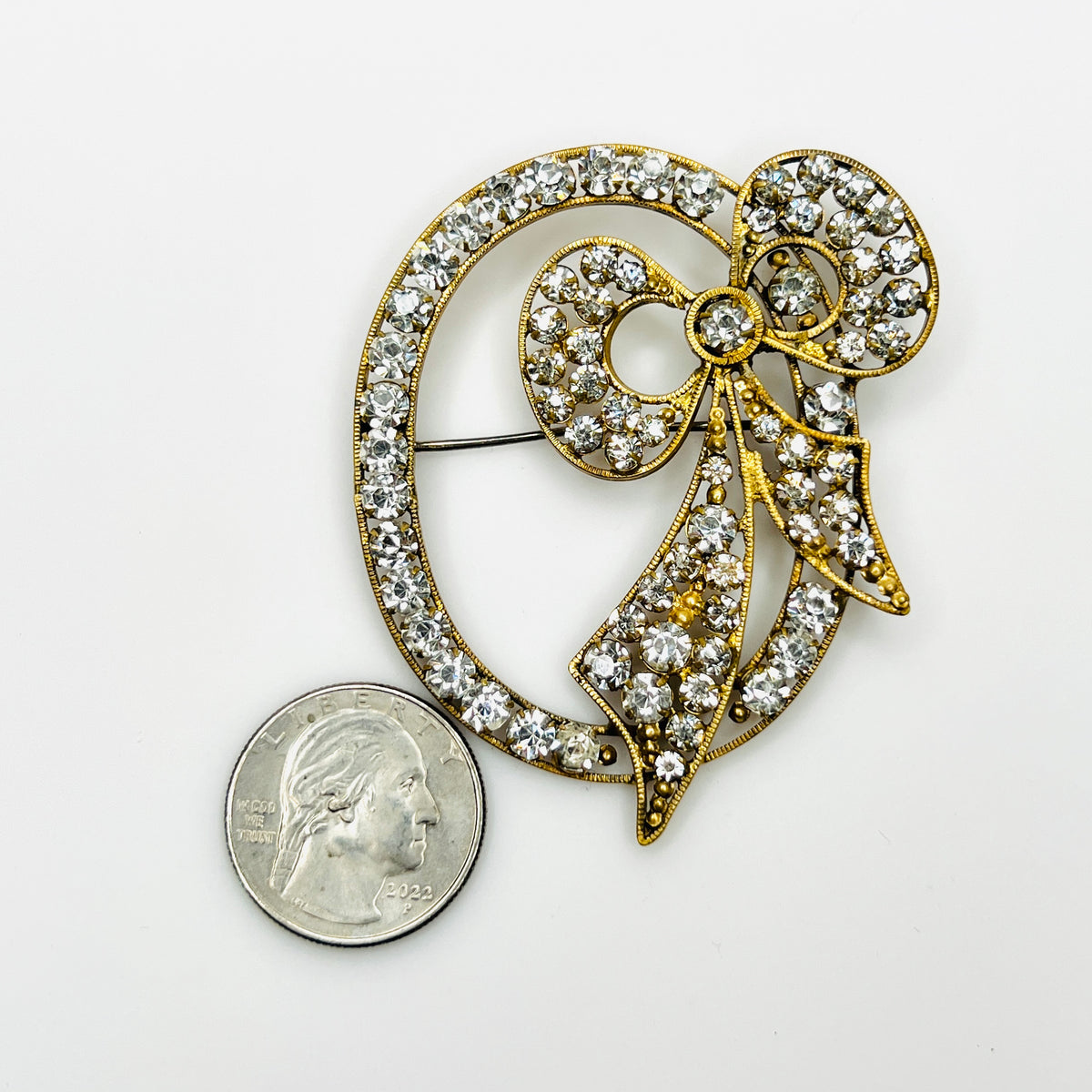 Czech rhinestone bow brooch beside a quarter, showing the scale of its open oval design.