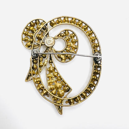 Reverse of Czech bow brooch showing pin closure, stone settings, and age-related metal wear.