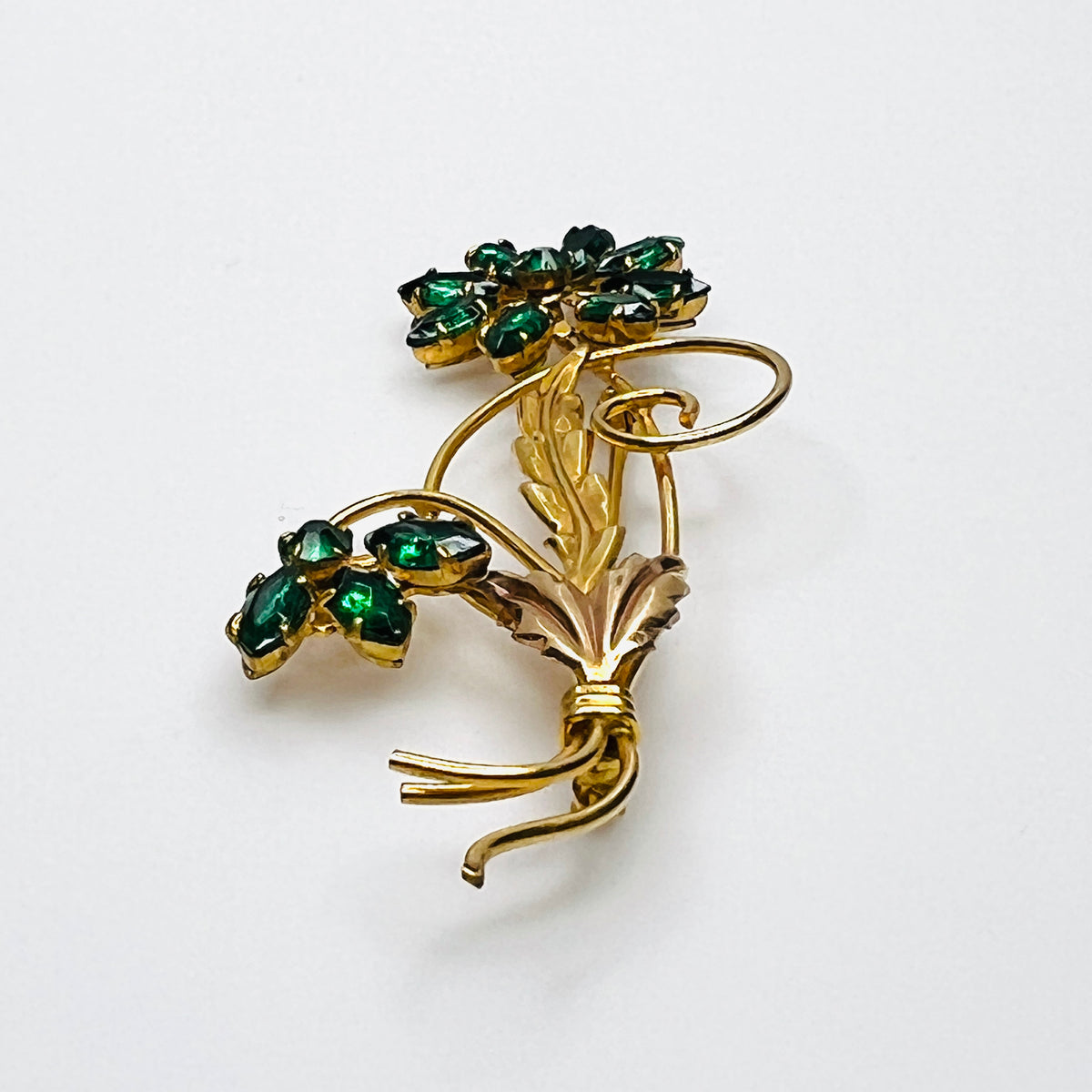 Side view of dimensional 12K gold filled floral brooch with green glass rhinestones