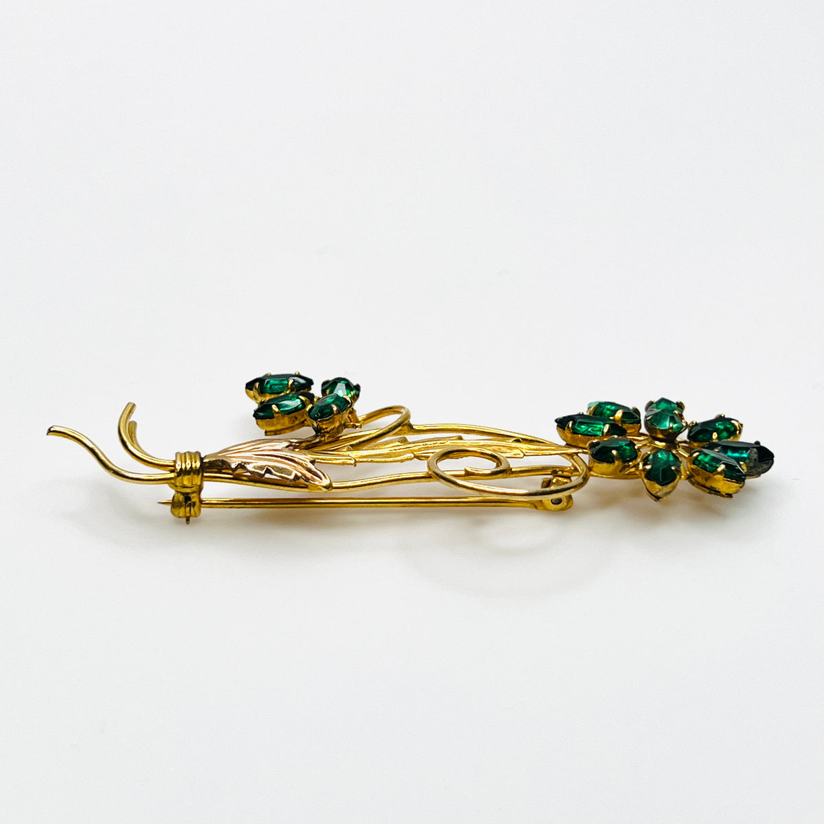 Side view of dimensional 12K gold filled floral brooch with green glass rhinestones