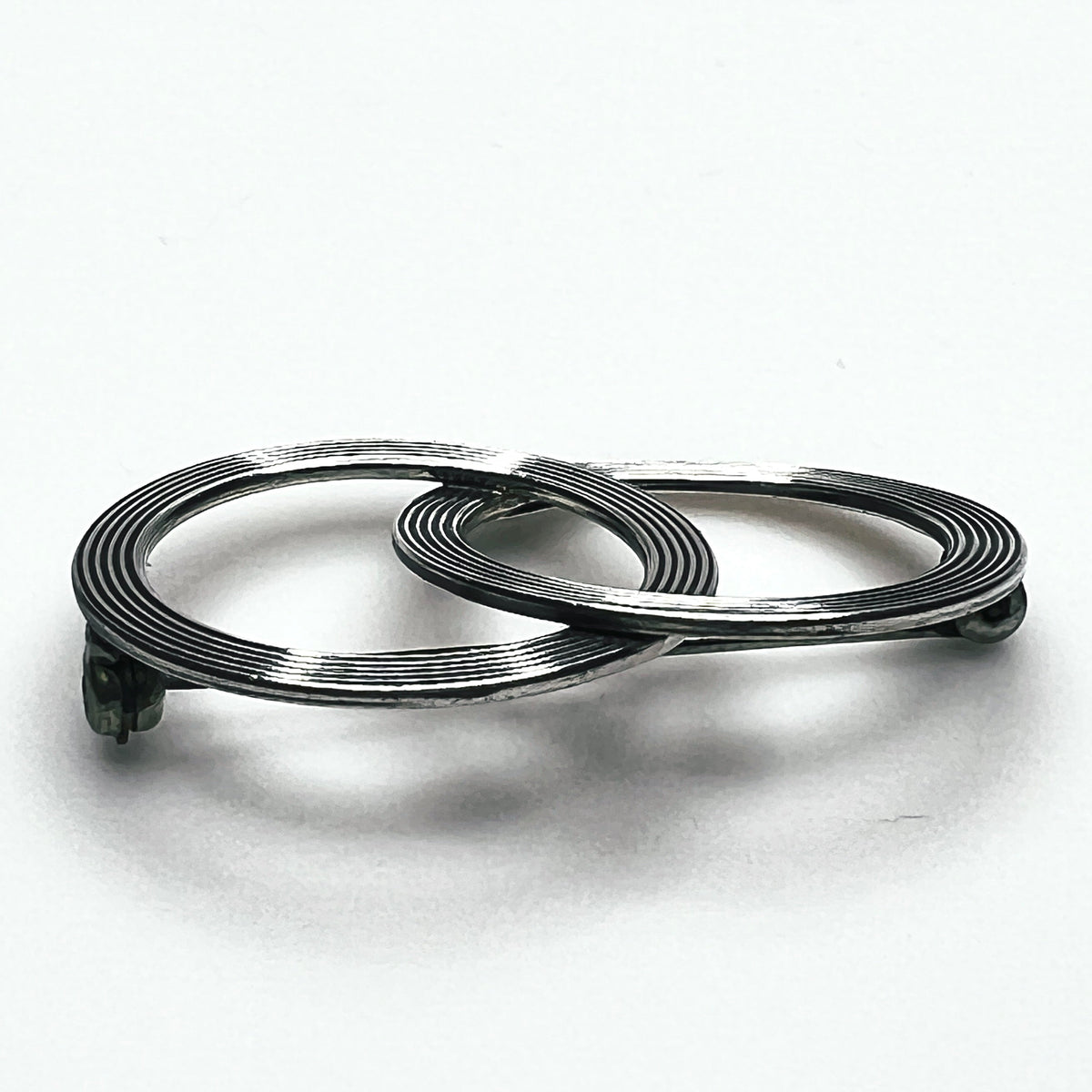 Side view of vintage Beau sterling silver Modernist brooch showing layered circular construction, dimensional profile and pin mechanism.