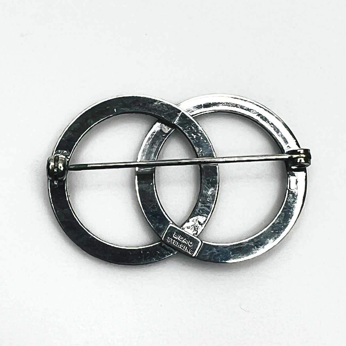 Reverse of vintage Beau sterling silver interlocking circle brooch showing pin stem, safety clasp and signed maker's plaque.