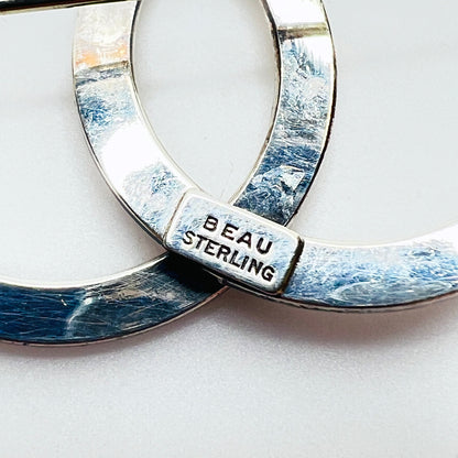 Close-up of BEAU STERLING maker's mark on reverse of vintage double circle sterling silver brooch.