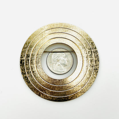 Oversized gold tone circle brooch shown with quarter for scale