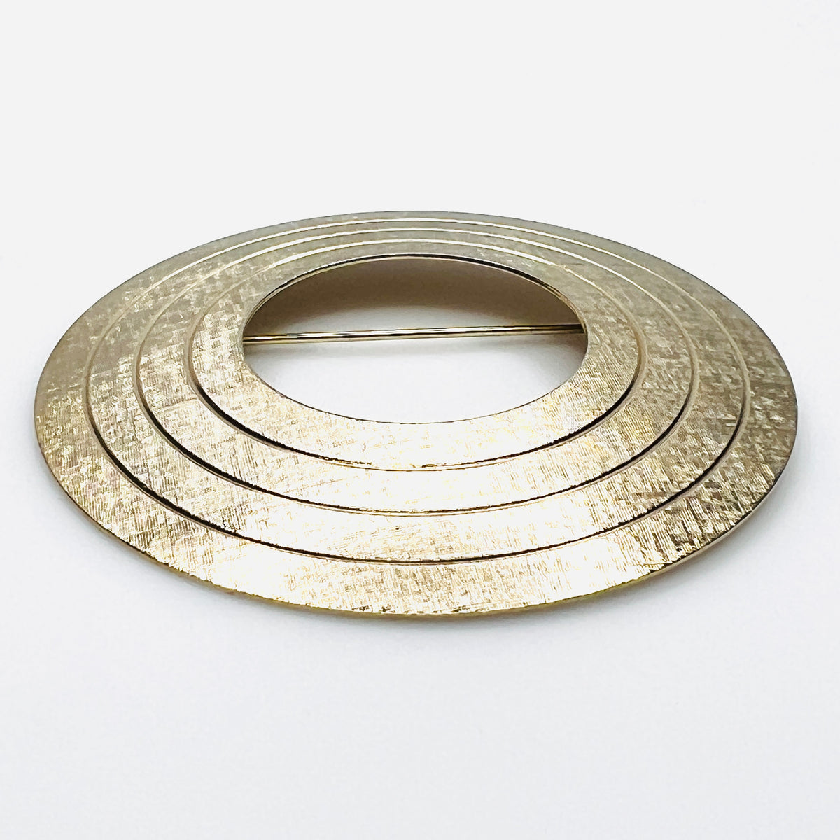 Side view of vintage textured gold tone concentric circle brooch