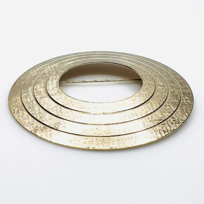 Side view of vintage textured gold tone concentric circle brooch