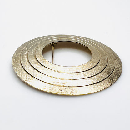Side view of vintage textured gold tone concentric circle brooch