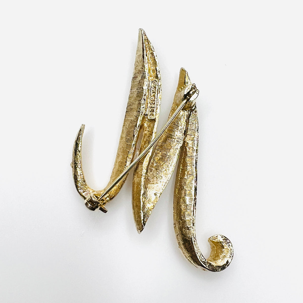 Reverse of signed Mamselle 1960s gold tone M or W initial brooch with pin closure