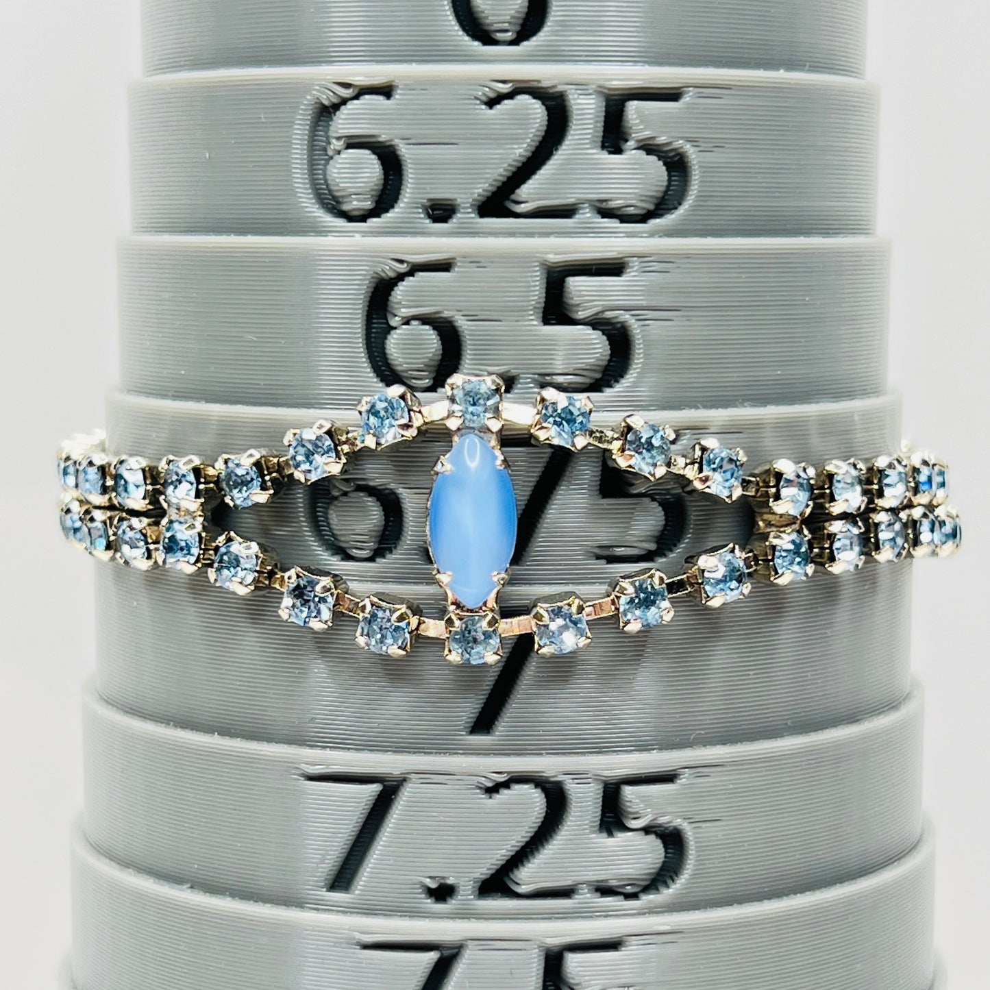 Blue rhinestone bracelet with marquise moonstone centerpiece displayed on bracelet sizer