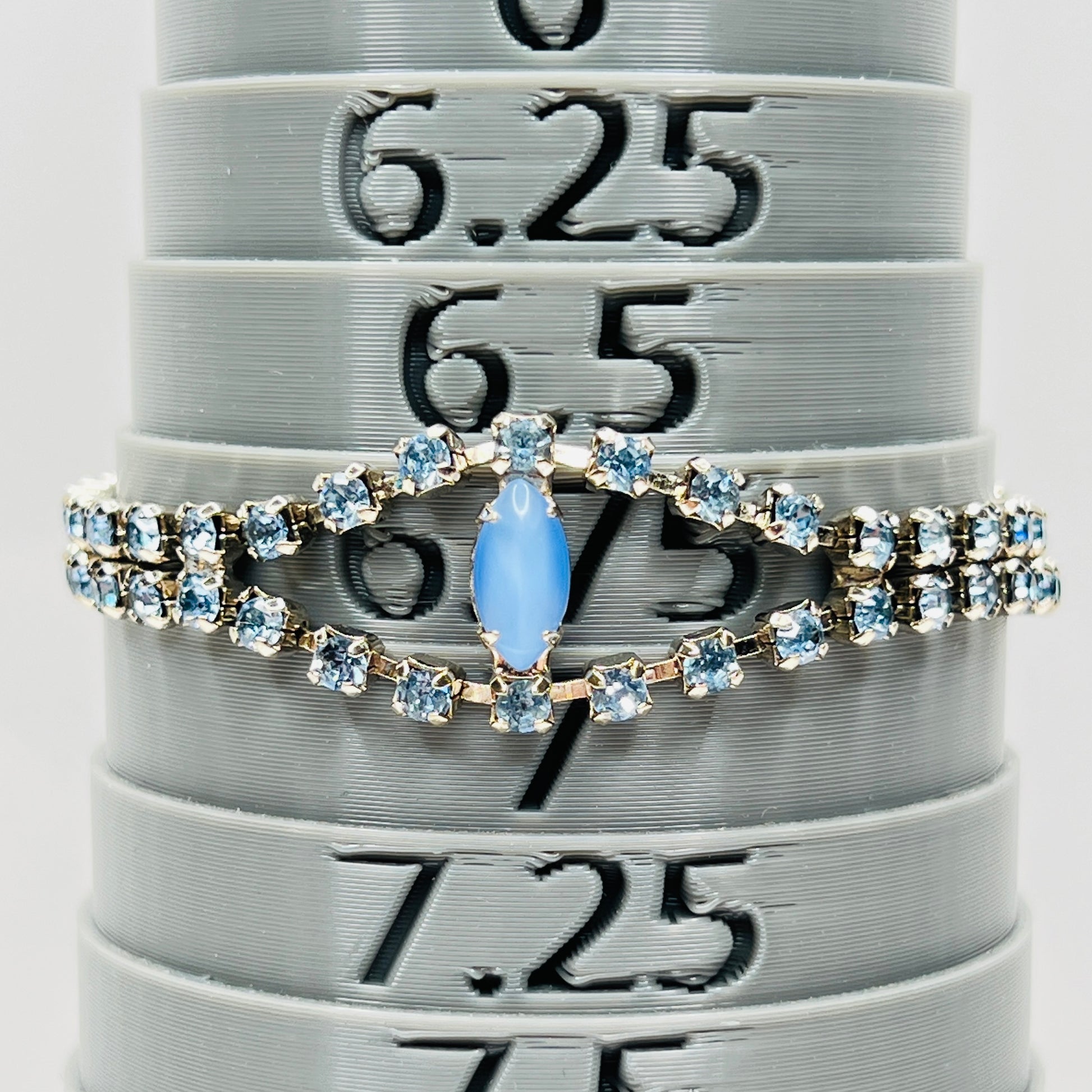 Blue rhinestone bracelet with marquise moonstone centerpiece displayed on bracelet sizer