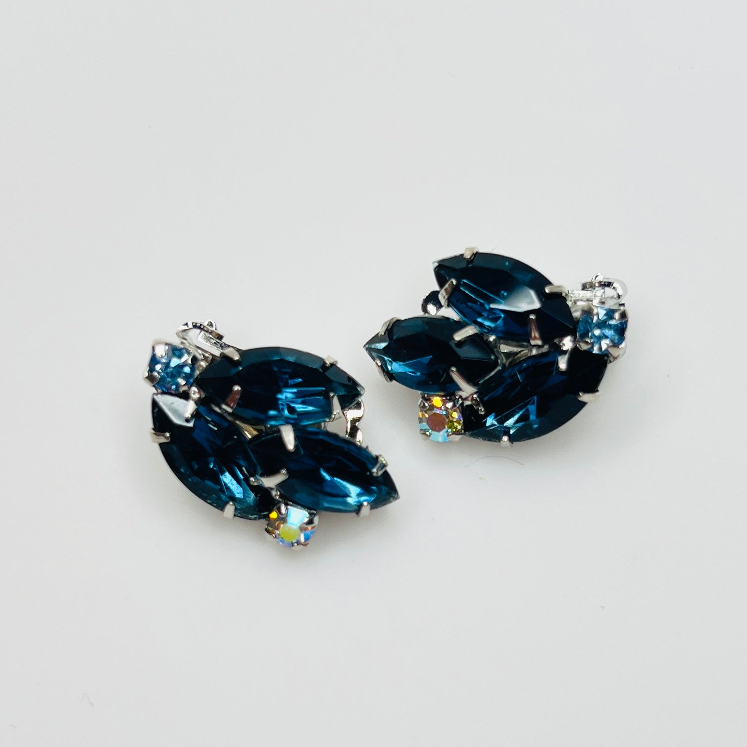 Vintage 1950s blue rhinestone clip-on earrings with marquise glass stones and aurora borealis accents.