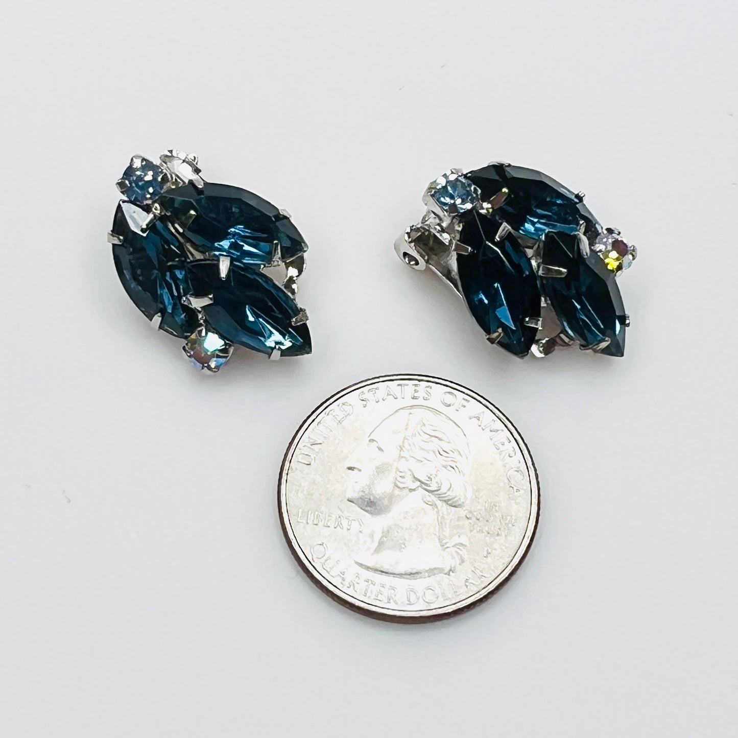 Blue rhinestone clip-on earrings beside a quarter for size reference.